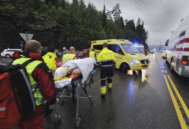 Medics and emergency workers escort youths from a camp site on the island of Utoya