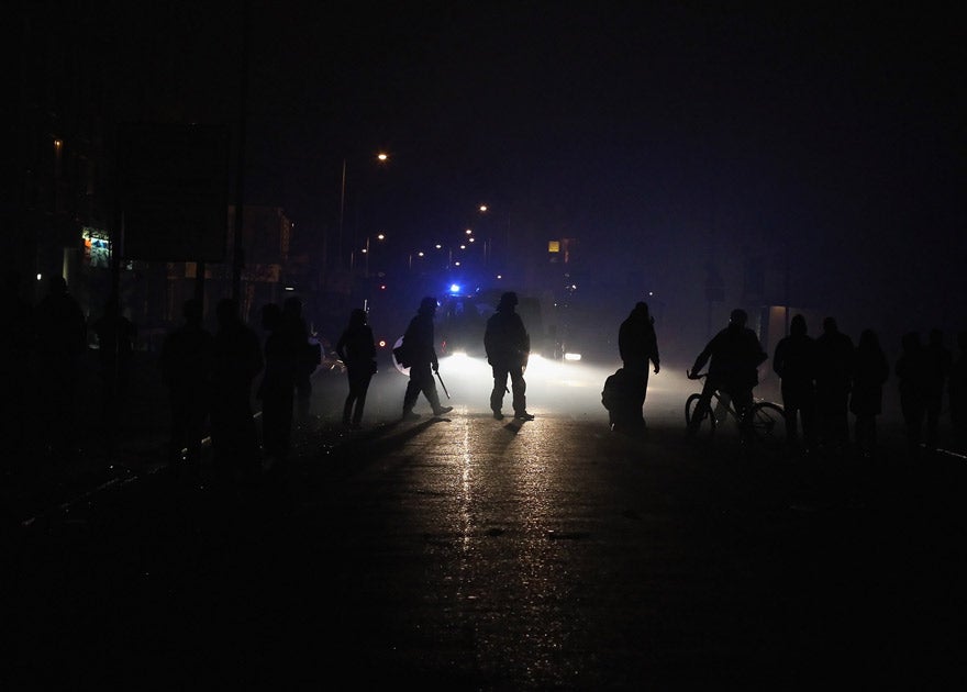 Police officers make their way down a blackened street after a blackout in Croydon, 8 August 2011