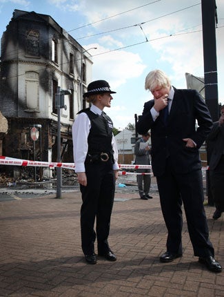 London Mayor Boris Johnson stands with Police Superintendent Jo Oakley near burnt out Reeves Corner furniture store