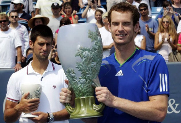 Andy Murray holds the championship trophy after defeating Novak Djokovic (left) in the final of the Cincinnati Masters yesterday