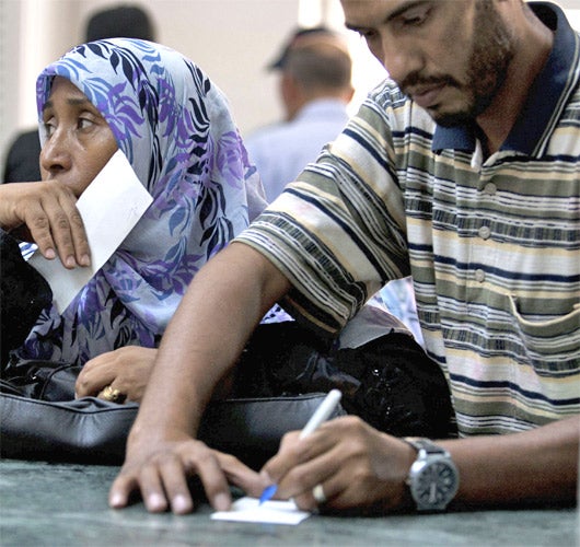 Libyans wait to get money from a bank recently reopened in Tripoli