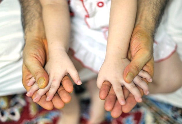 An Afghan migrant, Akbar, who does not want to be identified, holds his daughter during an interview in Kuala Lumpur