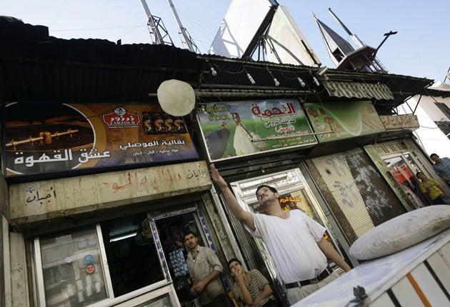 A baker preparing bread throws dough in the air in central Damascus