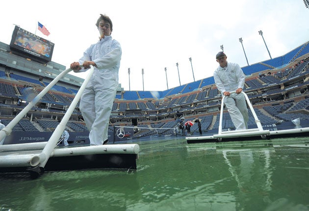 Ground staff attempt to clear the surface at Flushing Meadows after
more rain disrupted play yesterday
