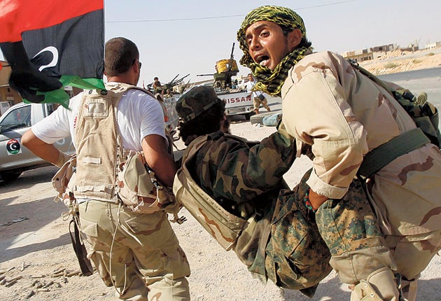 Rebel fighters carry a wounded comrade during the battle for Bani Walid