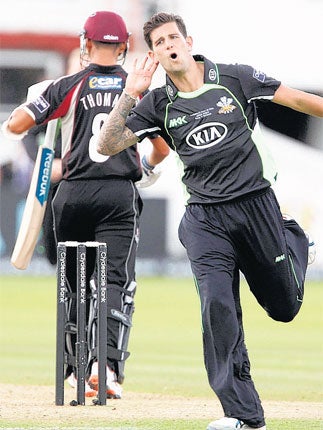 Man of the ear: Somerset batsman Alfonso Thomas heads for the pavilion as the Surrey bowler Jade Dernbach celebrates another wicket at Lord's