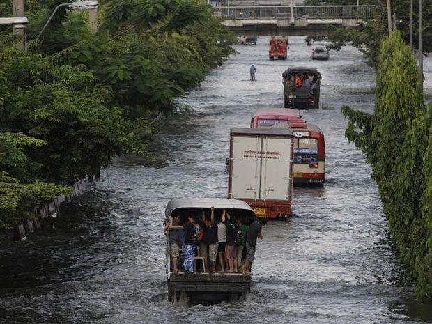 Thai residents hold on to a truck as they cross flooded streets in the Mon Chit area of Bangkok