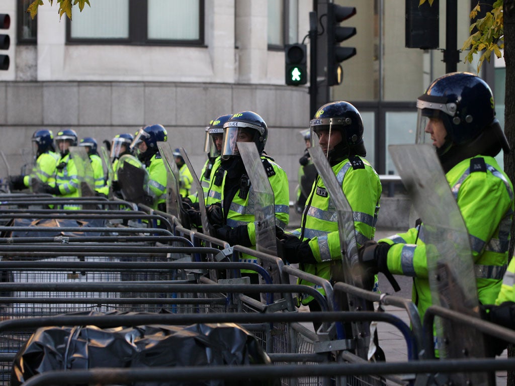 Standing guard: Police in riot gear man crowd control barriers lining the route