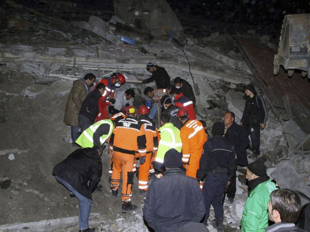 Rescue workers search for survivors in the rubble of a collapsed building in Van