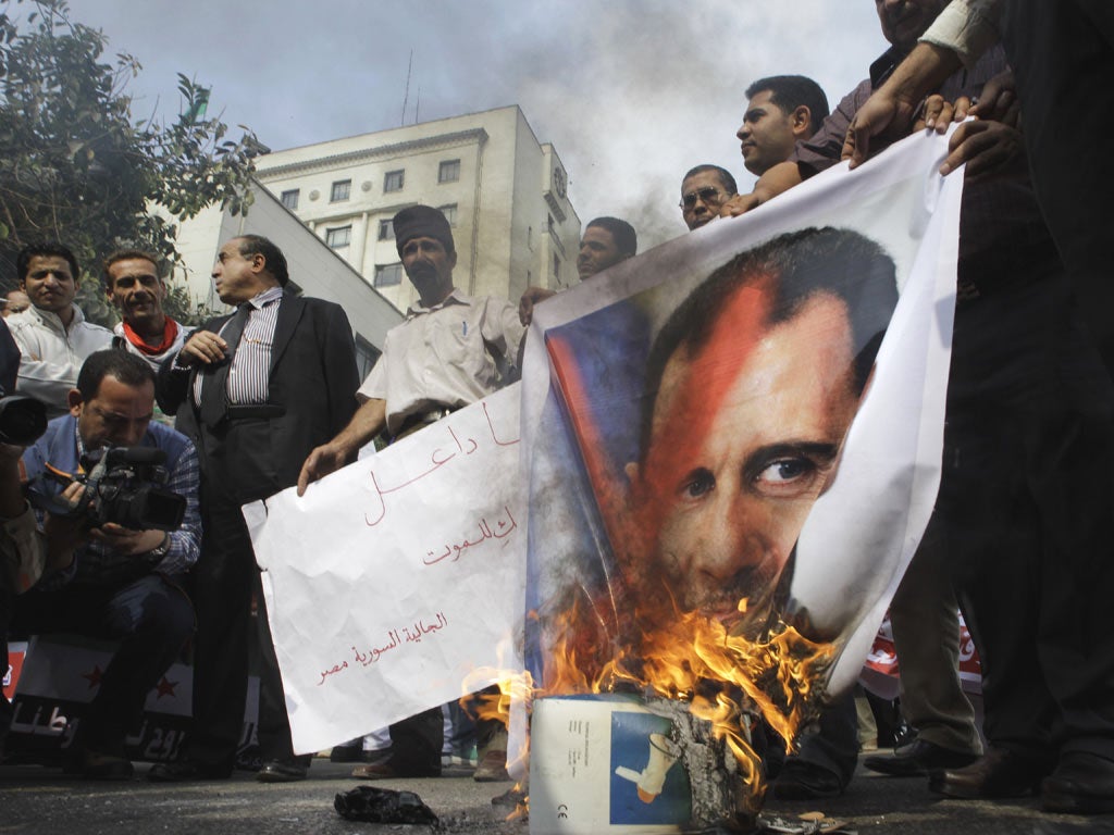 Syrian protesters burn a picture of Syrian President Bashar Assad during a protest
