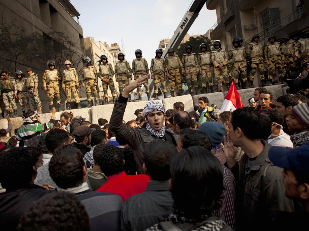 Protesters chant slogans close to a barricade near Tahrir Square, Cairo, yesterday