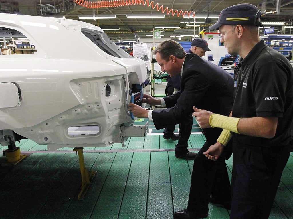 Prime Minister David Cameron installs a badge on a car at a Toyota plant in Burnaston in the East Midlands yesterday