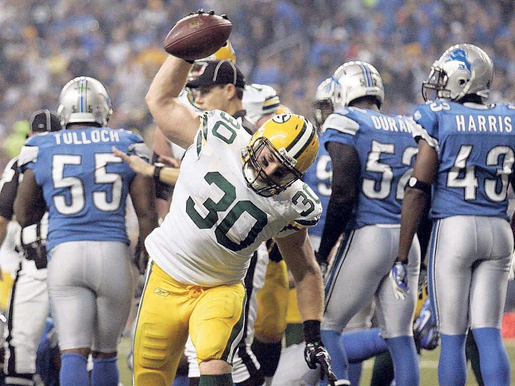 Green Bay’s John Kuhn spikes the ball after scoring a touchdown against Detroit