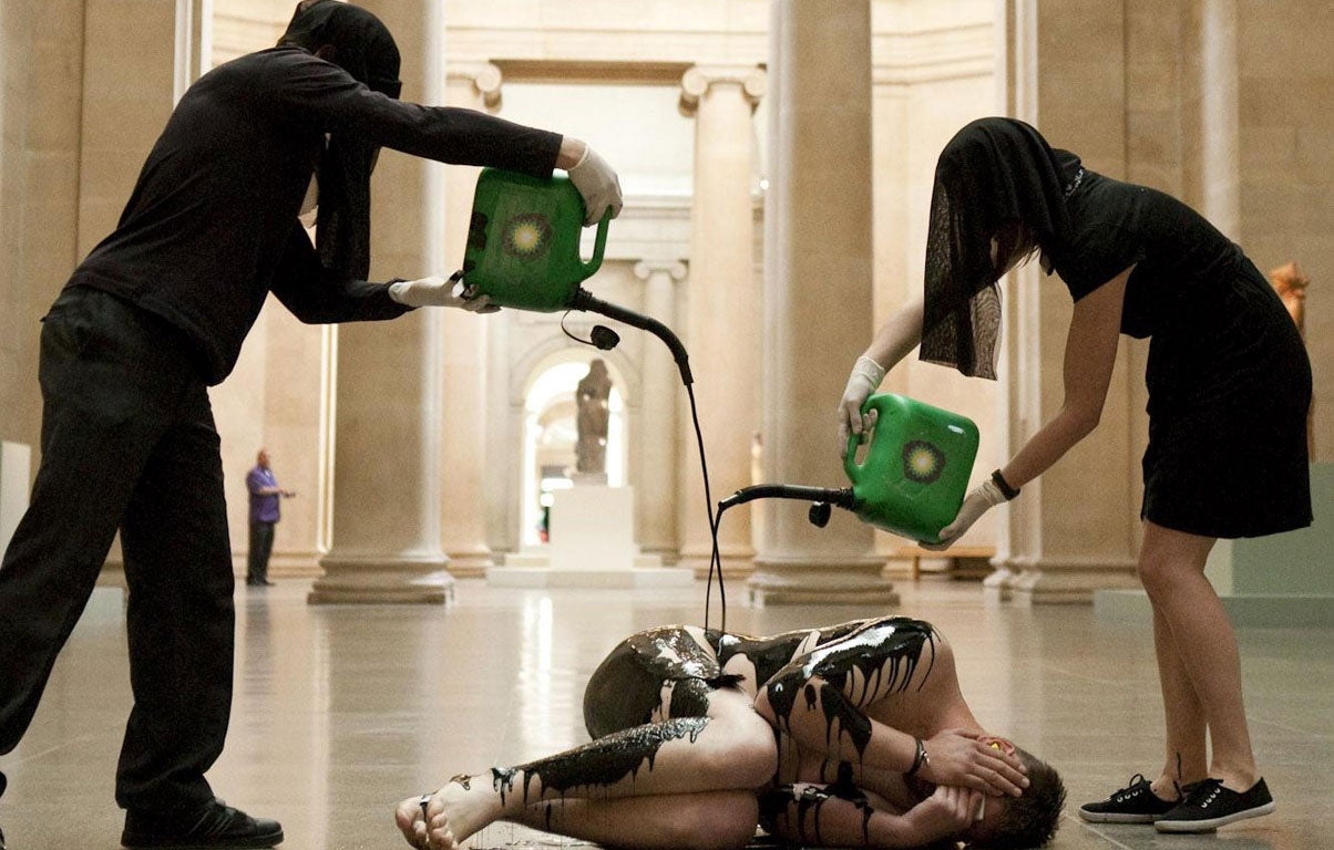 Activists from Liberate Tate pouran oil-like substance over a naked group member in the middle of the Tate Britain