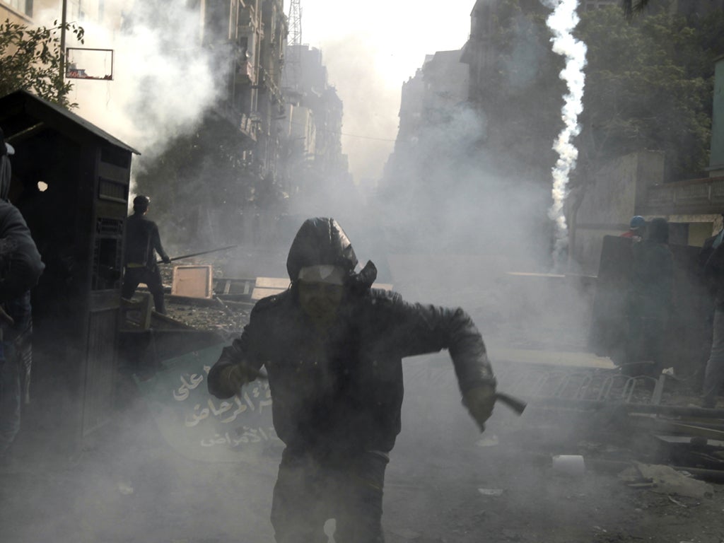 Egyptian protesters run for cover under clouds of tear gas on 23 November