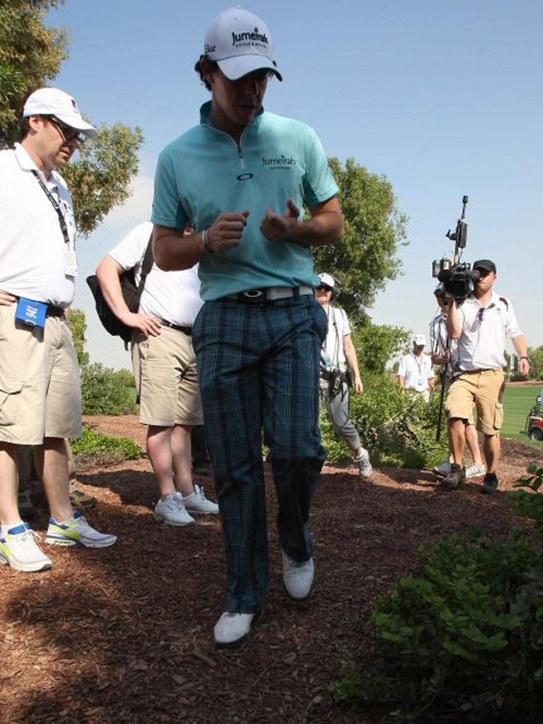 Rory McIlroy looks for his ball on the fourth hole, a rare moment of trouble in an otherwise superb round in Dubai