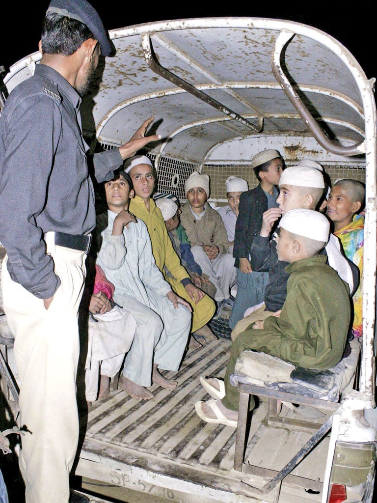 Boys who were held at the Zakariya madrassa in Karachi are taken away by police