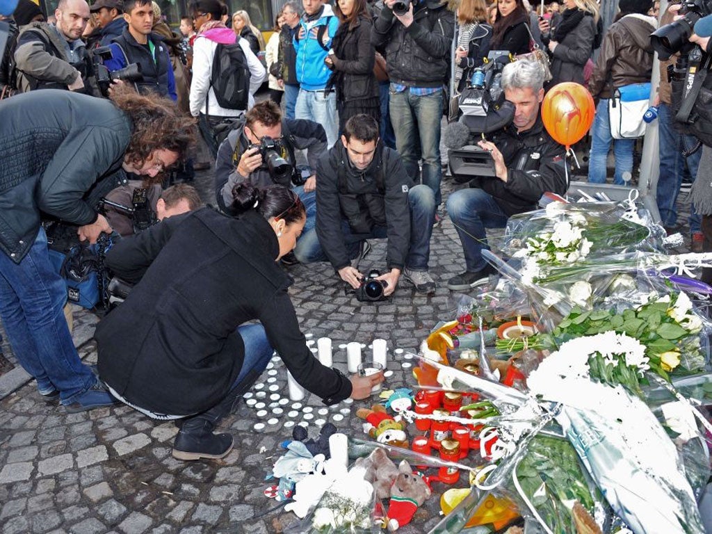 People display candles in a broken bus shelter, one of the targets of the shooting on the Place Saint-Lambert in Liege