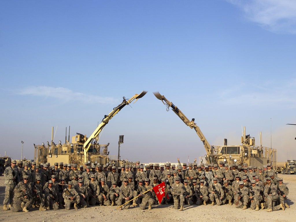 <p>Soldiers pose with their unit’s flag at a base near Nasiriyah before their departure</p>