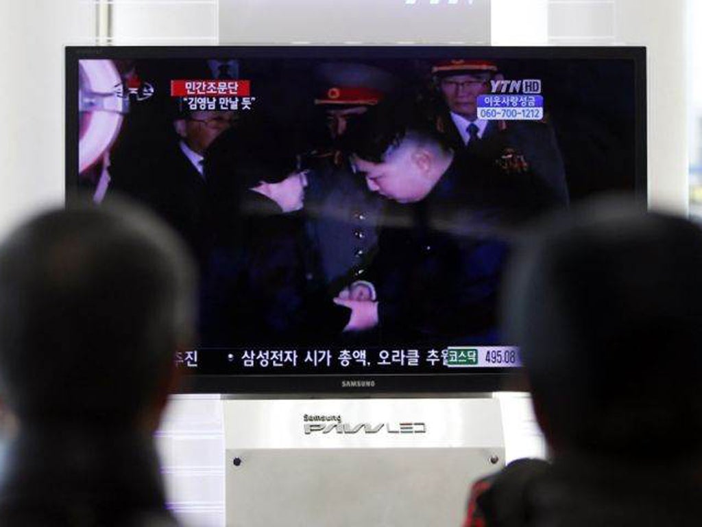 South Koreans watch a TV screen showing Kim Jong-un, right, greet the wife of former South Korean President Kim Dae-jung, Lee Hee-ho