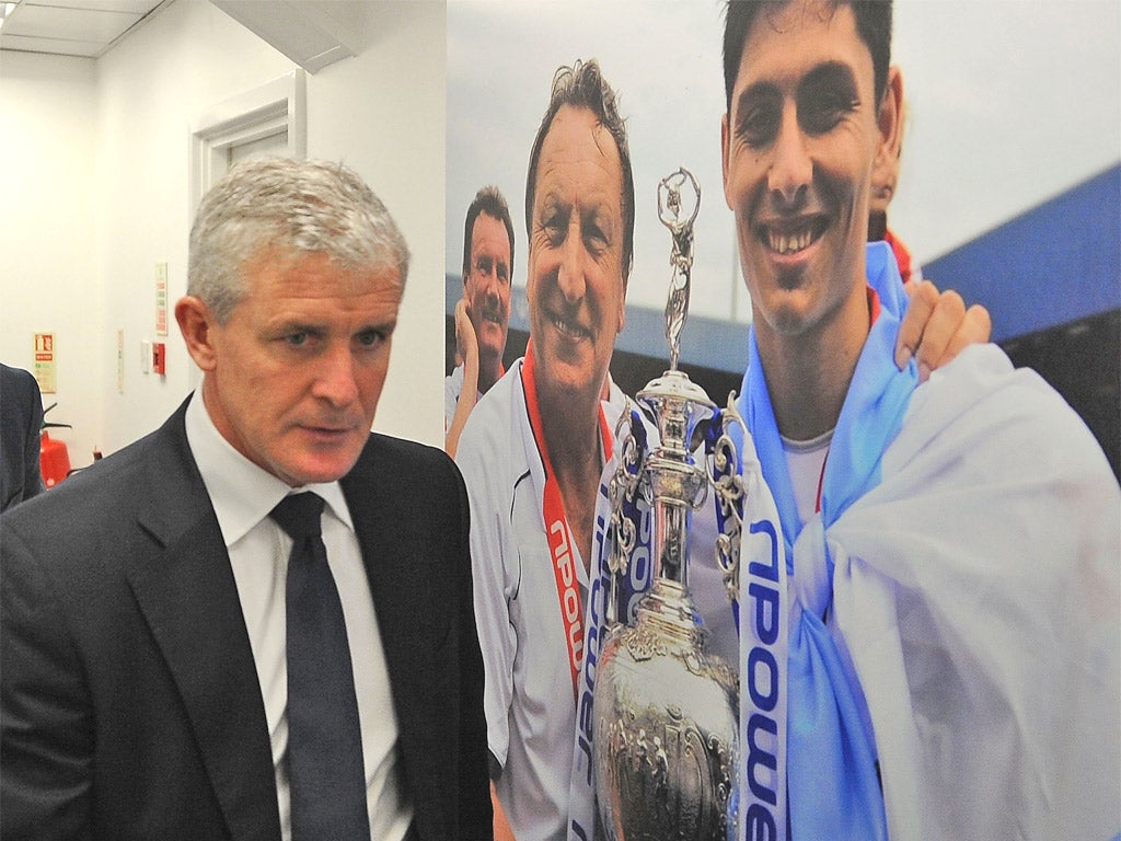 Mark Hughes walks past a picture of his predecessor Neil Warnock at Loftus Road yesterday