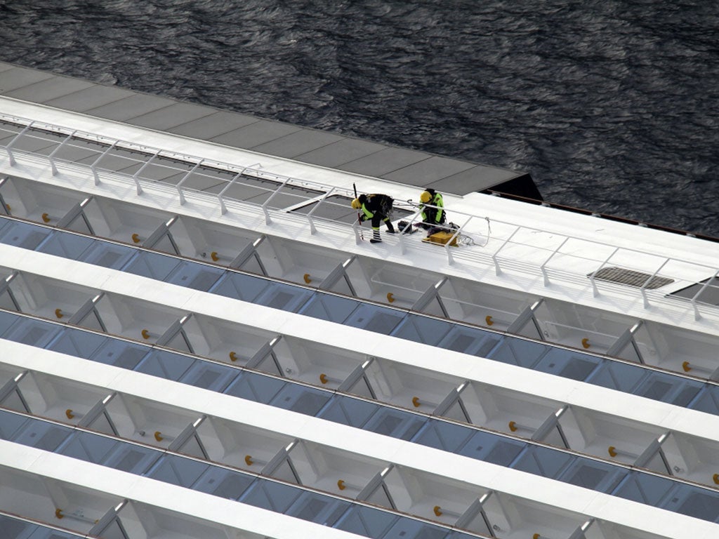 Firefighters work on the side of the Costa Concordia yesterday