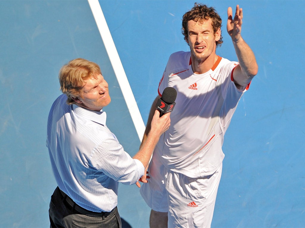 Andy Murray gestures up towards new coach Ivan Lendl in the stands during his post-match interview with Jim Courier