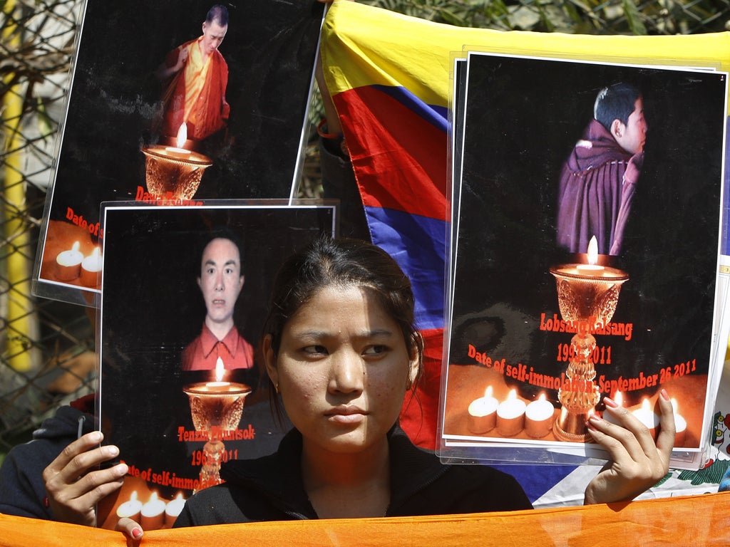 A Tibetan exile holds the photographs of Tibetan monks who have self immolated in Tibet protesting Chinese government, during a demonstration to support three fellow Tibetan exile students