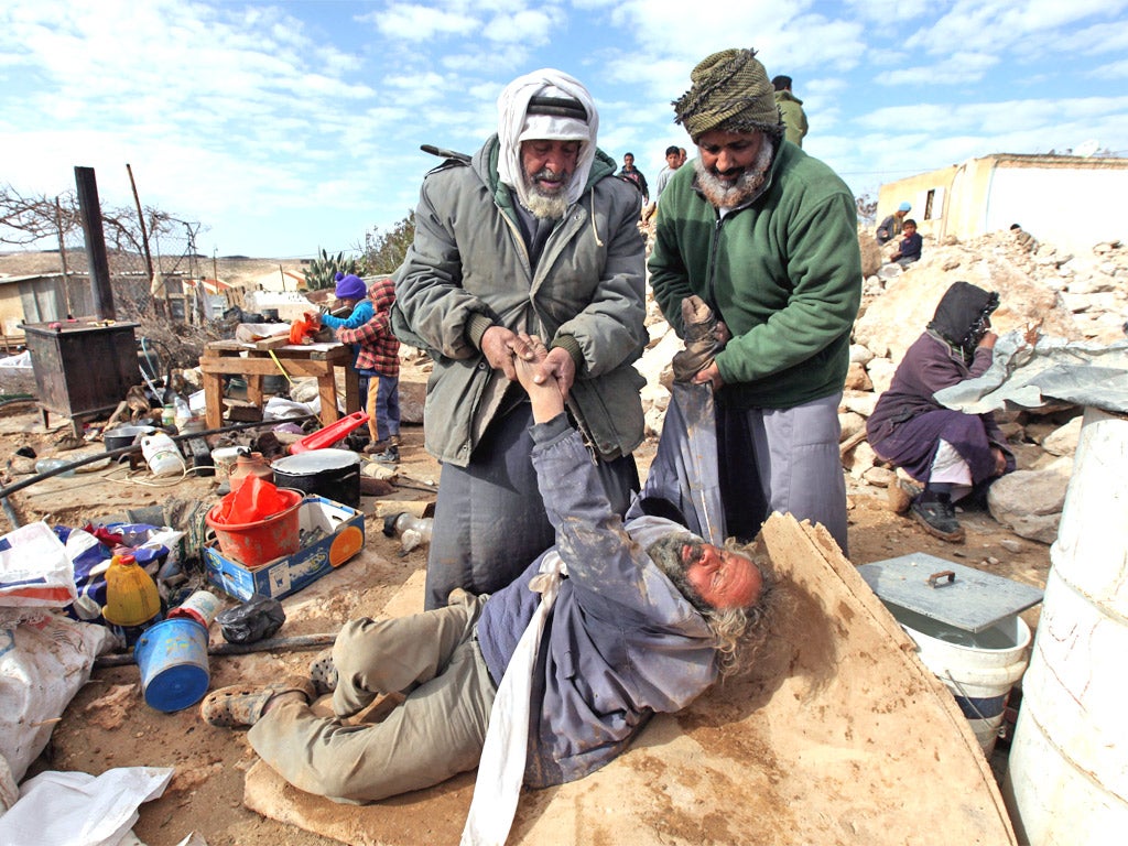 A Palestinian man is helped back to his feet after Israeli bulldozers destroyed a tin shack in Um al-Kheir, in the occupied West Bank region of Hebron yesterday