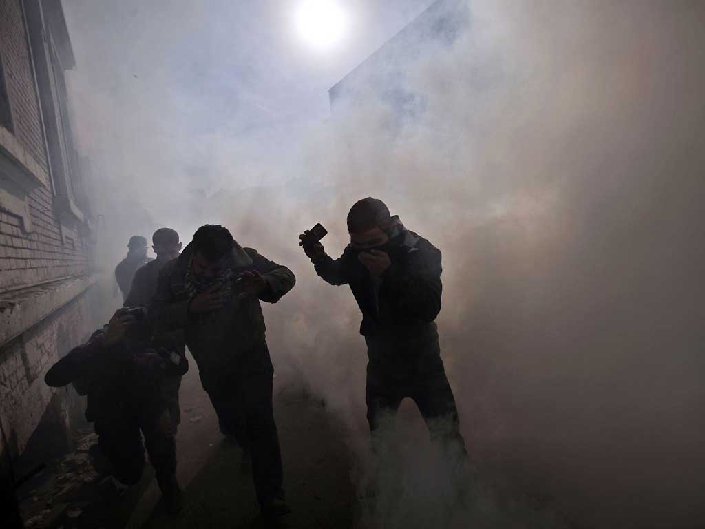 Egyptian protesters react as they get caught by tear gas fired by security forces during clashes near the Interior Ministry in Cairo