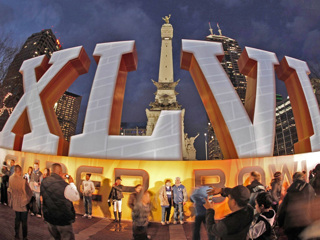 Fans pose for photos in front of a sign for Super Bowl XLVI on Monument Circle in Indianapolis