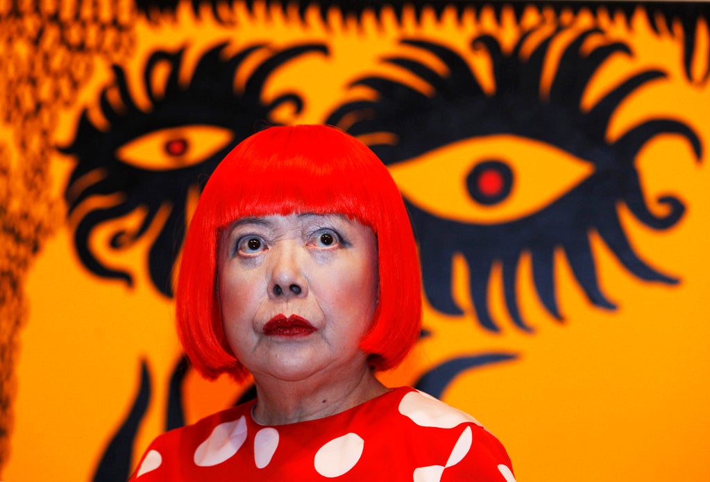 Artist Yayoi Kusama poses for a photograph with her artwork "Love arrives at the Earth Carrying with it a Tale of the Cosmos" at the Tate Modern gallery in London