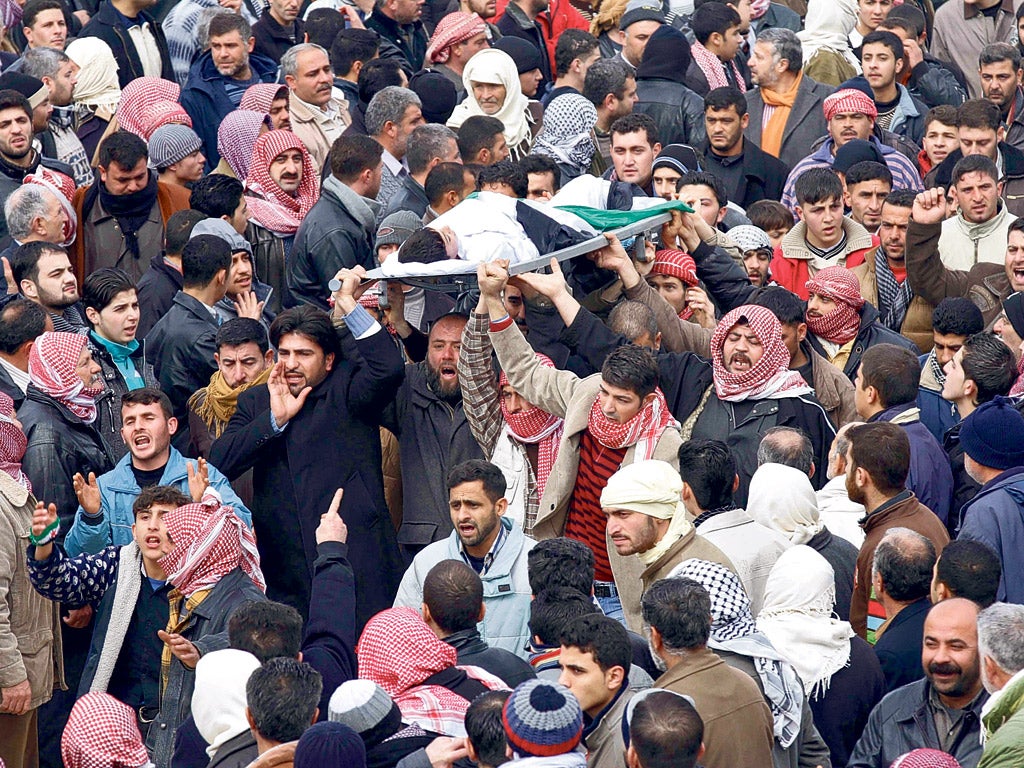 Mourners carry a 10-year-old boy killed during clashes with security forces in the city of Idlib to his funeral yesterday