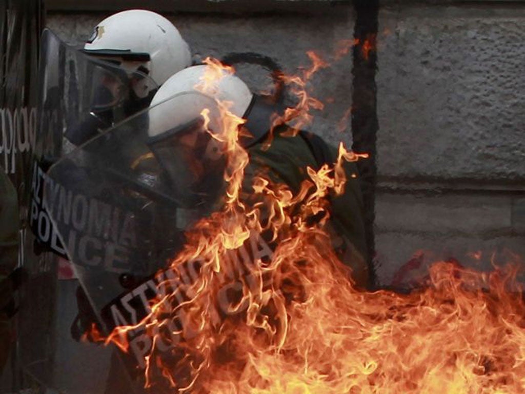 A petrol bomb explodes near riot police during demonstrationsin Athens