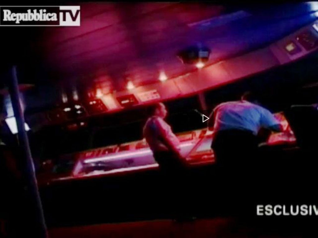 A man said to be Schettino is seen hunched over the controls on the bridge