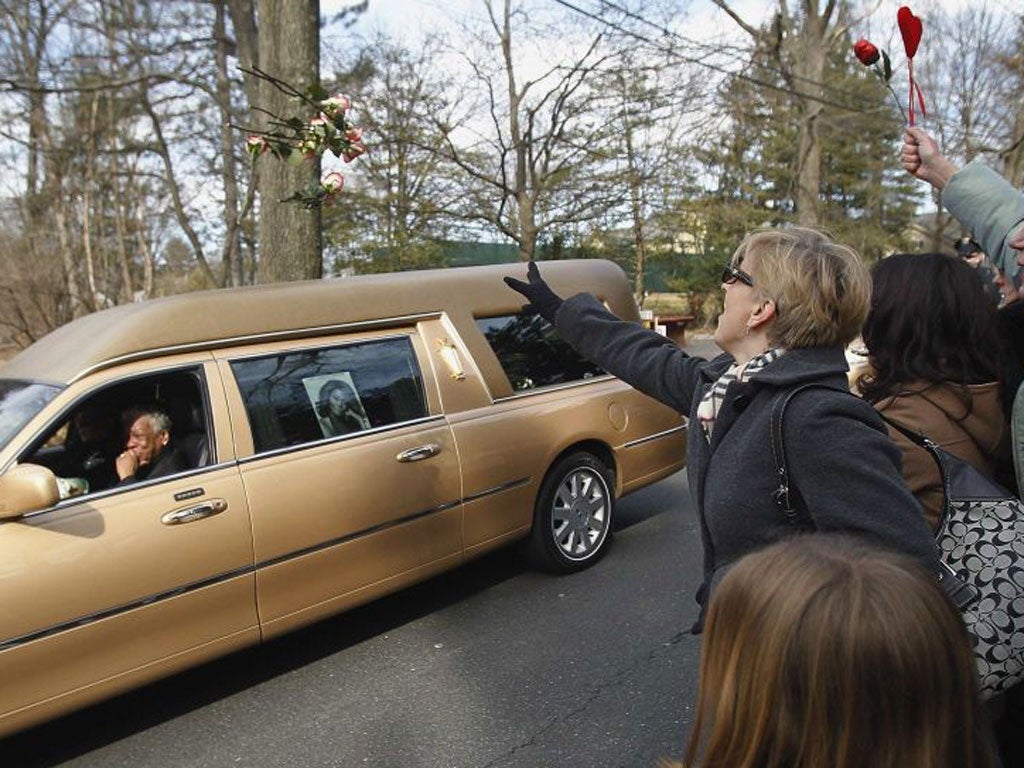 Mourners throw flowers on the hearse carrying Whitney Houston