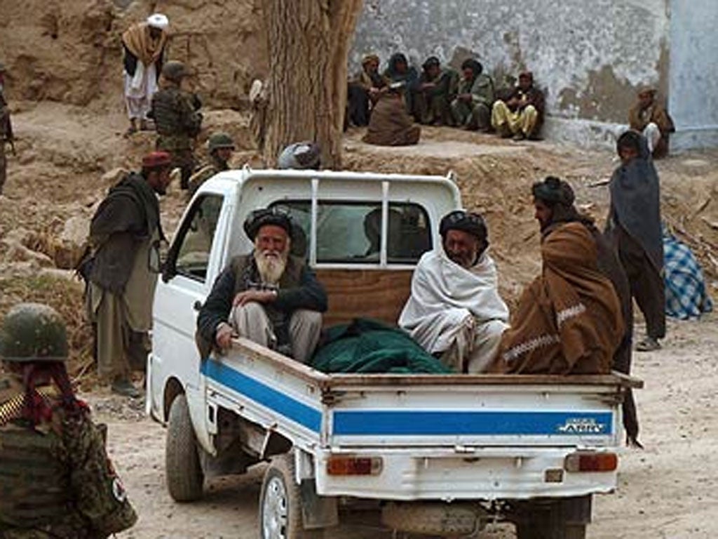Afghan villagers prepare to remove the victims of Sunday's shooting