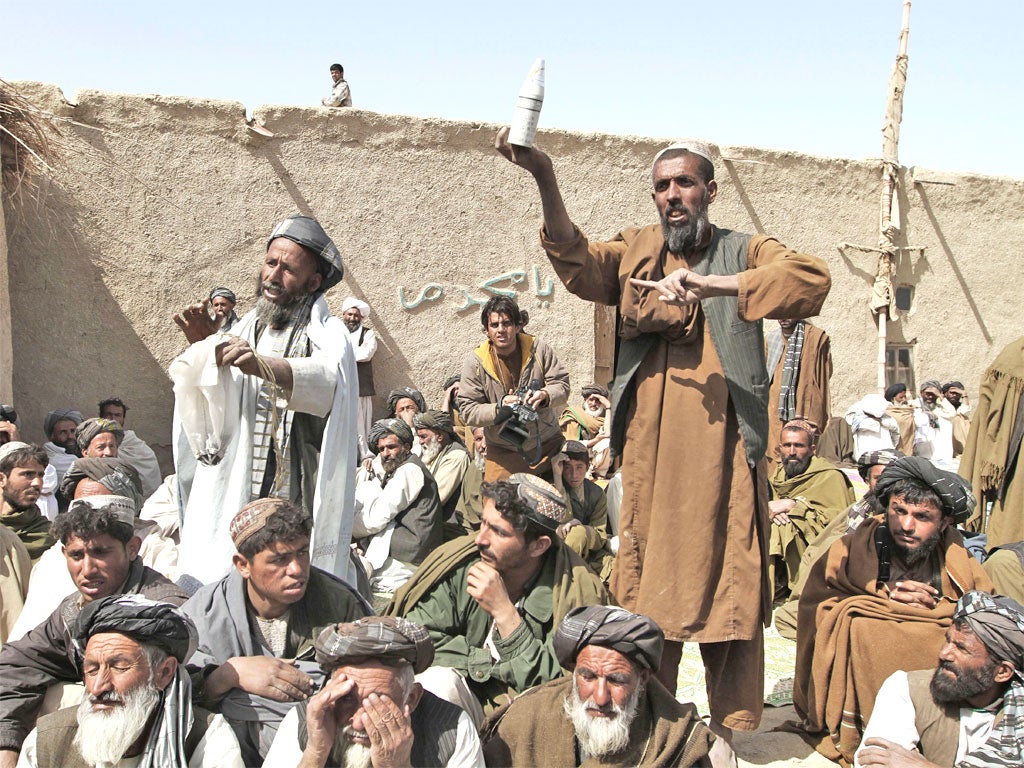 An Afghan villager shows an empty canister allegedly used during Sunday's shootings to the delegation