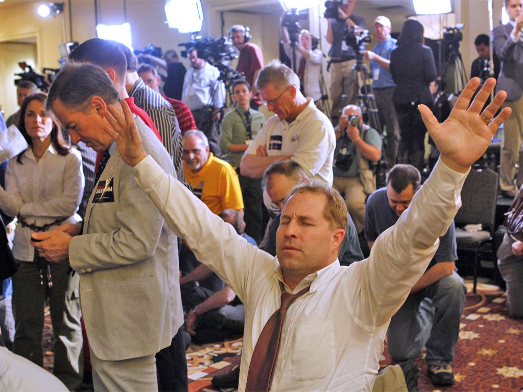 Supporters of Rick Santorum pray as they wait for him to speak after his victory in Lafayette, Louisiana