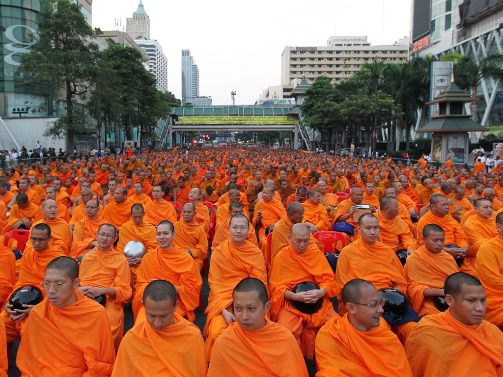 Thai Buddhist monks gather to receive food during an alms offering ceremony at Ratchaprasong