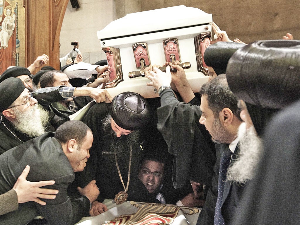 Pallbearers struggle to carry the coffin of Coptic Pope Shenuda III out of Saint Mark's cathedral during his funeral service yesterday