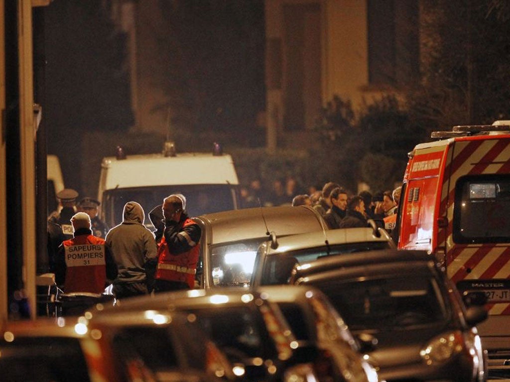 French Police officers and firefighters stand at night next to the apartment building where the suspect in the shooting at the Ozar Hatorah Jewish school is still barricaded
