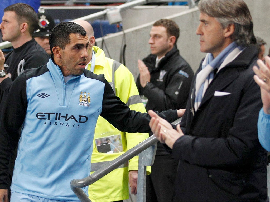 Carlos Tevez walks past his manager Roberto Mancini and on to the bench before last night's match with Chelsea at the Etihad