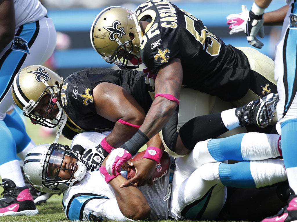 New Orleans Saints players Will Smith and Jonathan Casillas leave Cam Newton of Carolina Panthers down and out during an NFL match