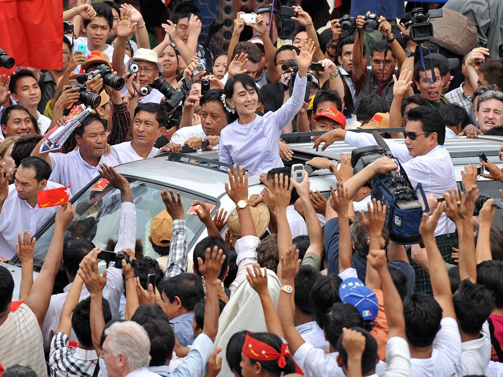 Myanmar opposition leader Aung San Suu Kyi waves to the crowd as she leaves National League for Democracy headquarters after addressing journalists
and supporters in