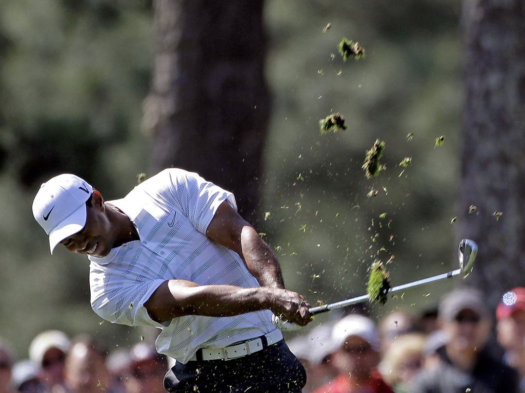 Please replace divots: Tiger Woods churns up the turf on the first fairway as he looks to drag himself back into contention