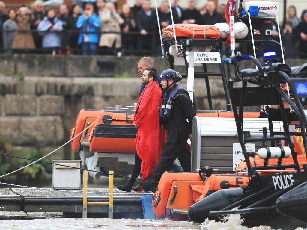 Protester Trenton Oldfield is led away by officials after being pulled from the Thames