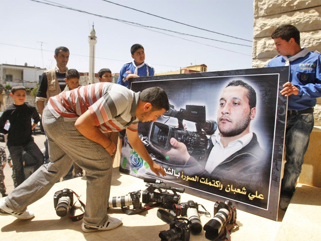 Colleagues laying down cameras in front of a portrait of the Lebanese cameraman Ali Shabaan at his funeral in the village of Maifadoun