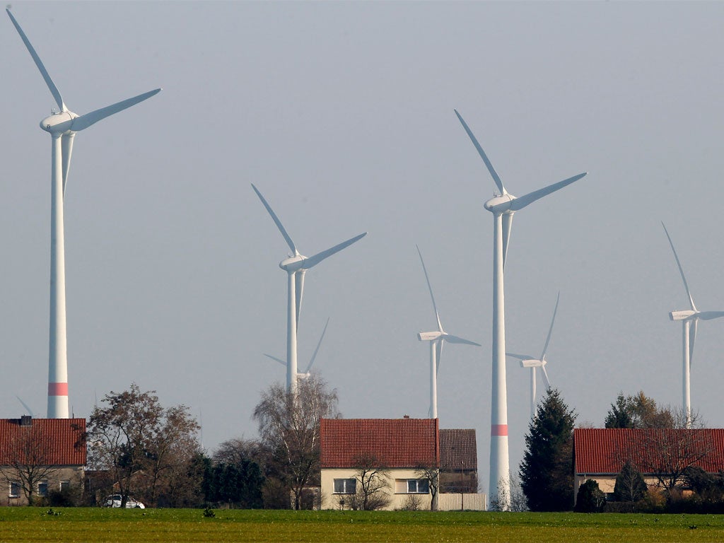 Wind turbines stand behind houses of the village of Feldheim