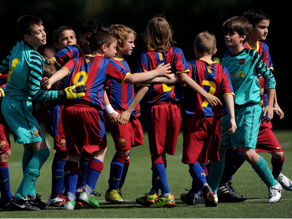 Pure kidology: Barcelona's youngsters form a huddle before kick-off at the club's La Masia training ground; they play in exactly the same way as the senior team